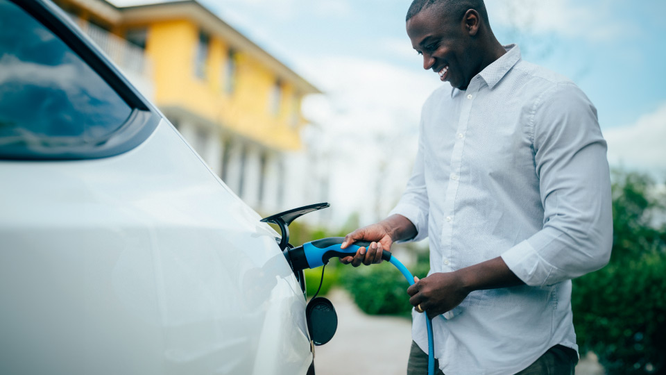 Man plugging EV charging cable into white car