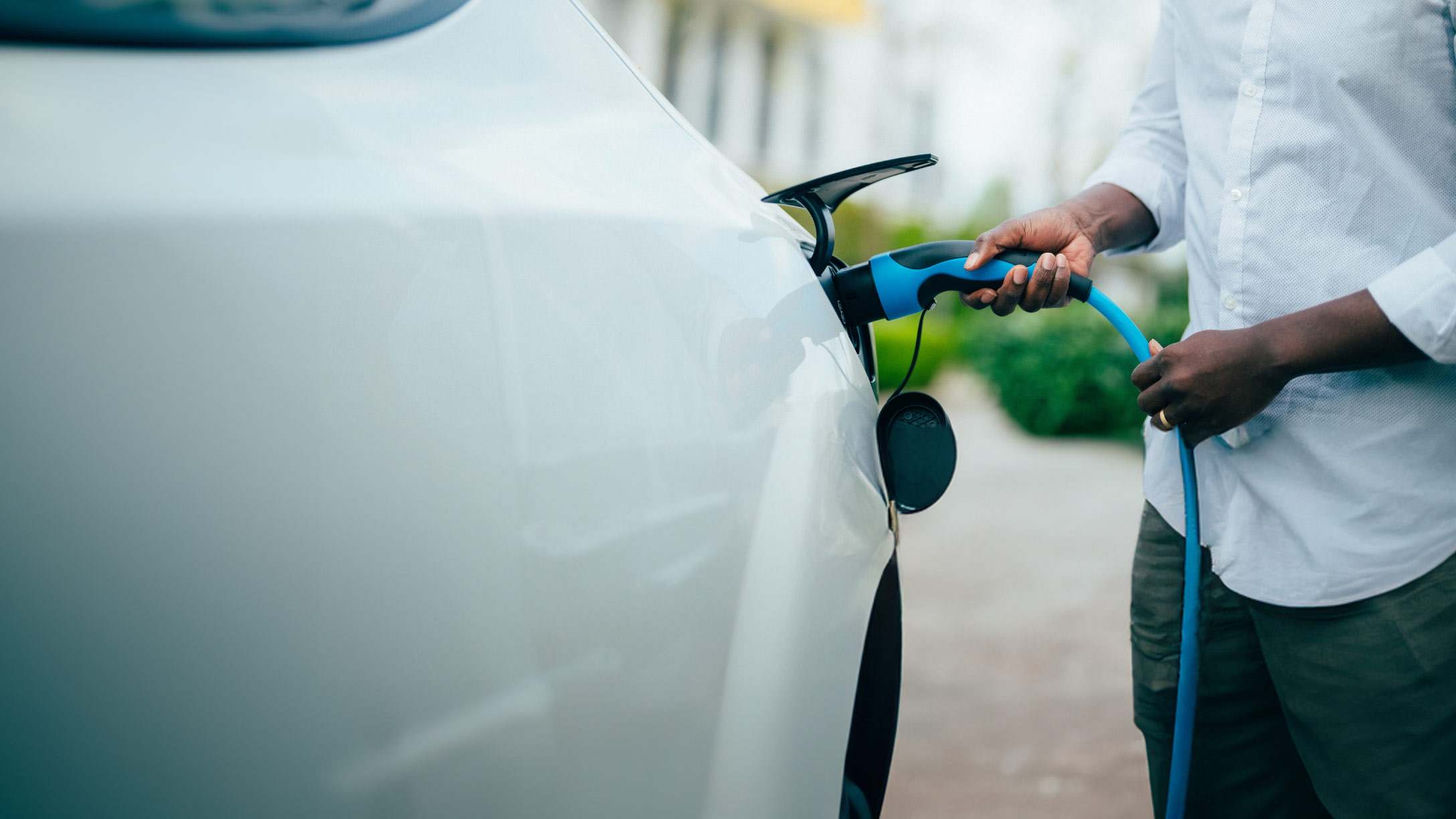 Man plugging EV charging cable into white car