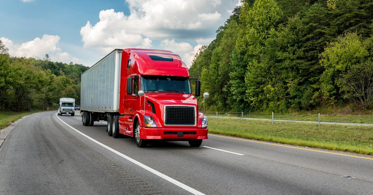 Trucks driving on highway beside trees