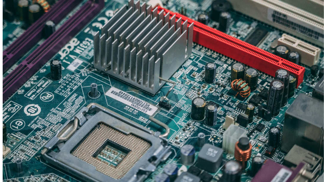 A computer motherboard with a CPU socket, heat sink, and red RAM slot
