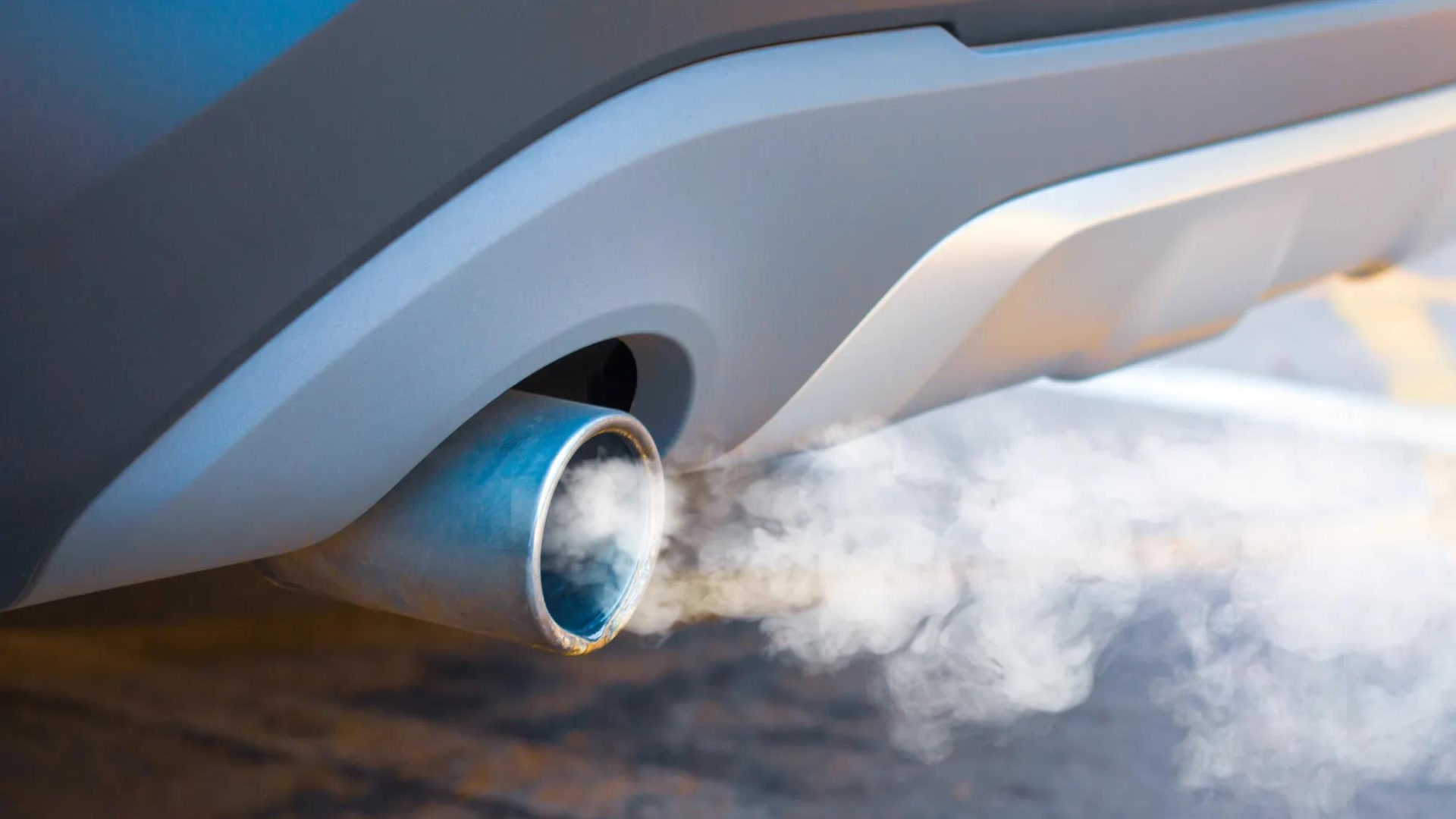 Nahaufnahme eines Autoapuffohrs mit blauem Glühelement, aus dem weiße Abgase ausströmen