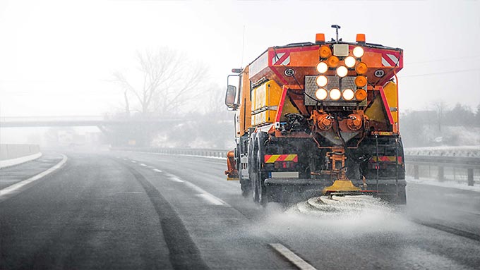 Orangefarbener Schneepflug beim Schneepflügen