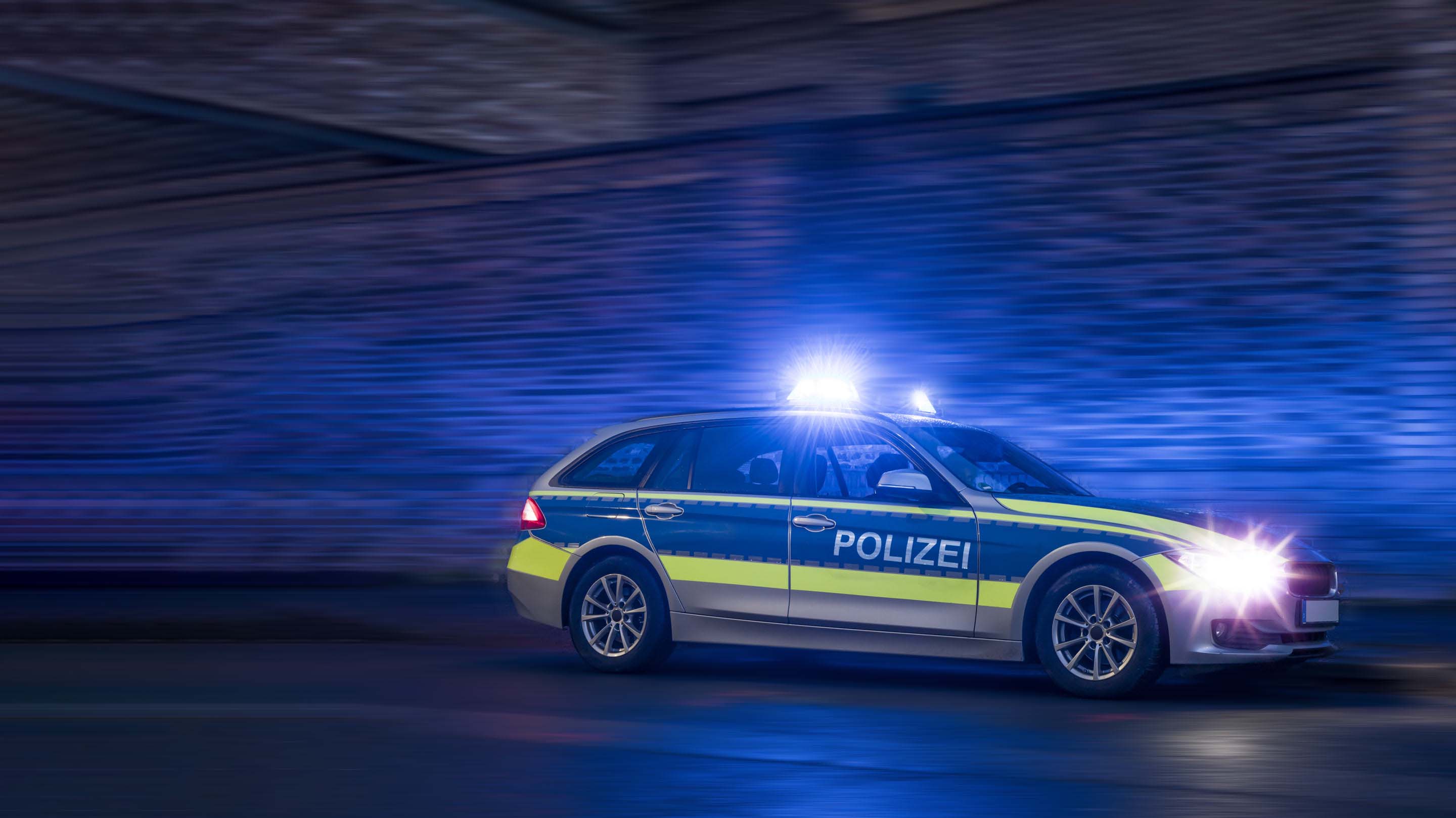 Heck eines Polizeifahrzeugs mit roten Lichtern im Hintergrund