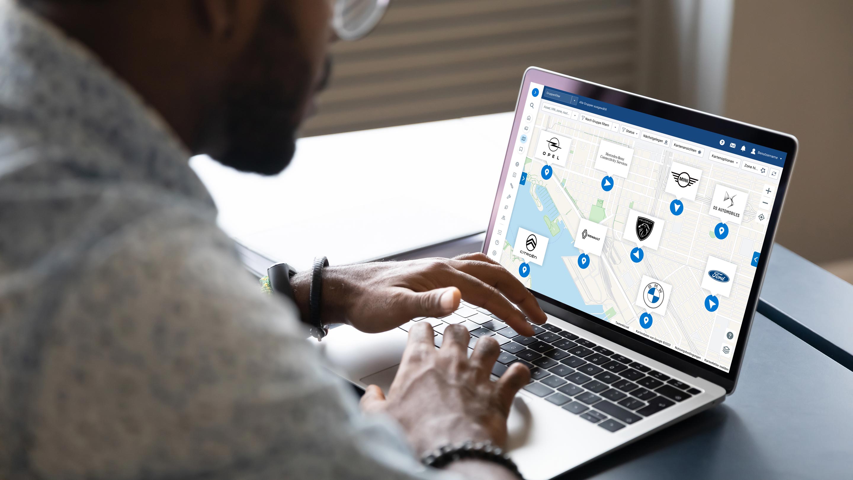 Mann arbeitet am Laptop und zeigt MyGeotab-Karten-UI mit verschiedenen OEM-Logos