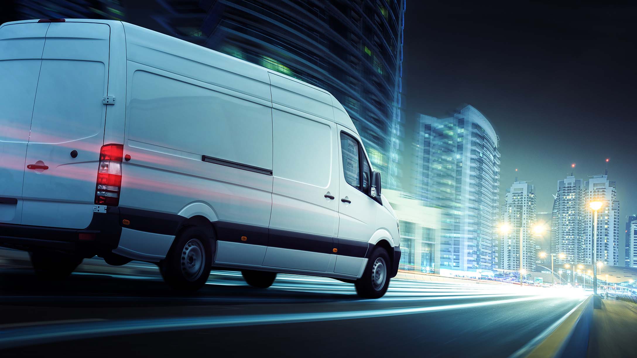 Image of a white van driving at night on a city road