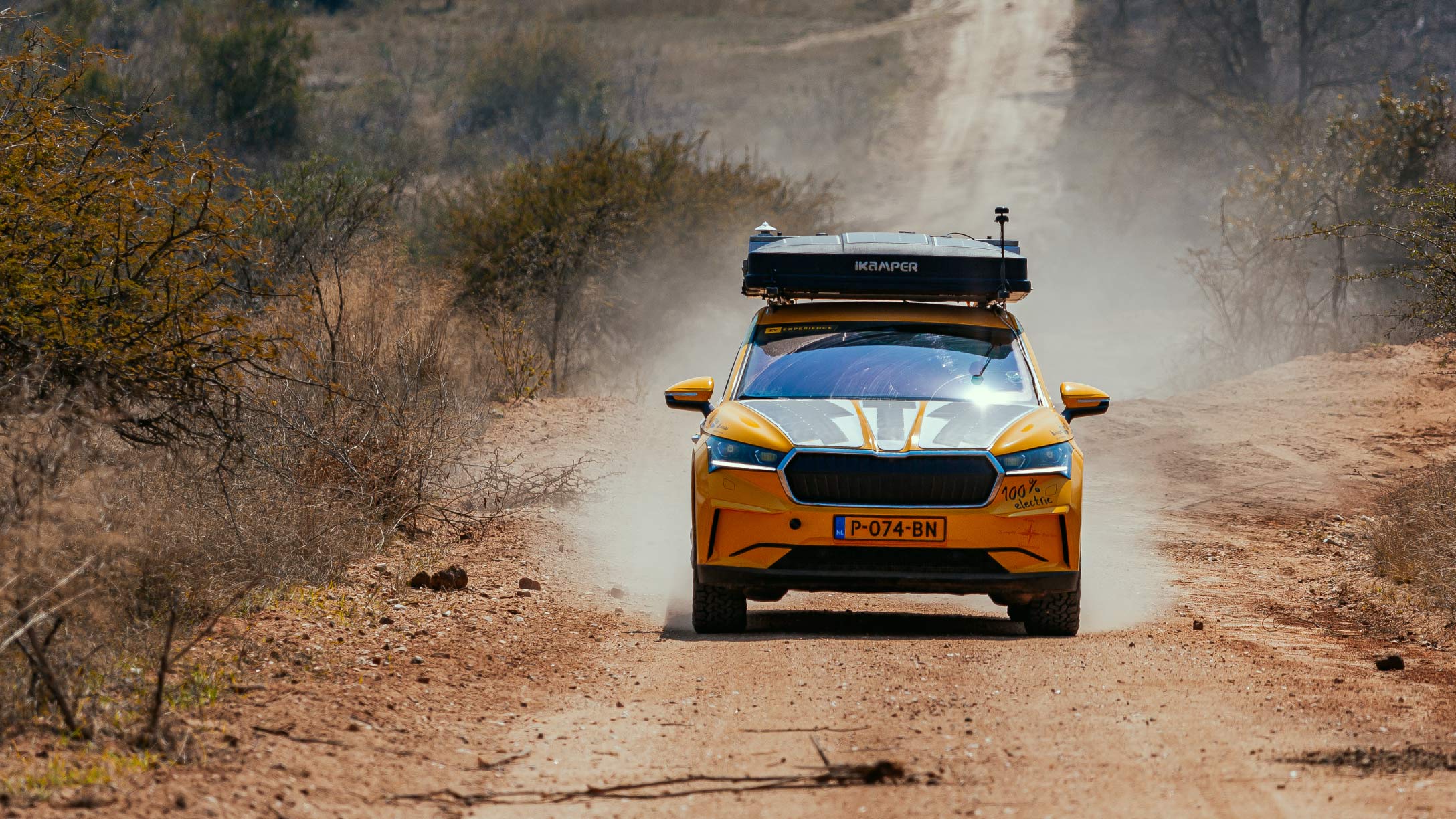 Veicolo elettrico giallo della spedizione 4x4 correndo su una strada sterrata africana