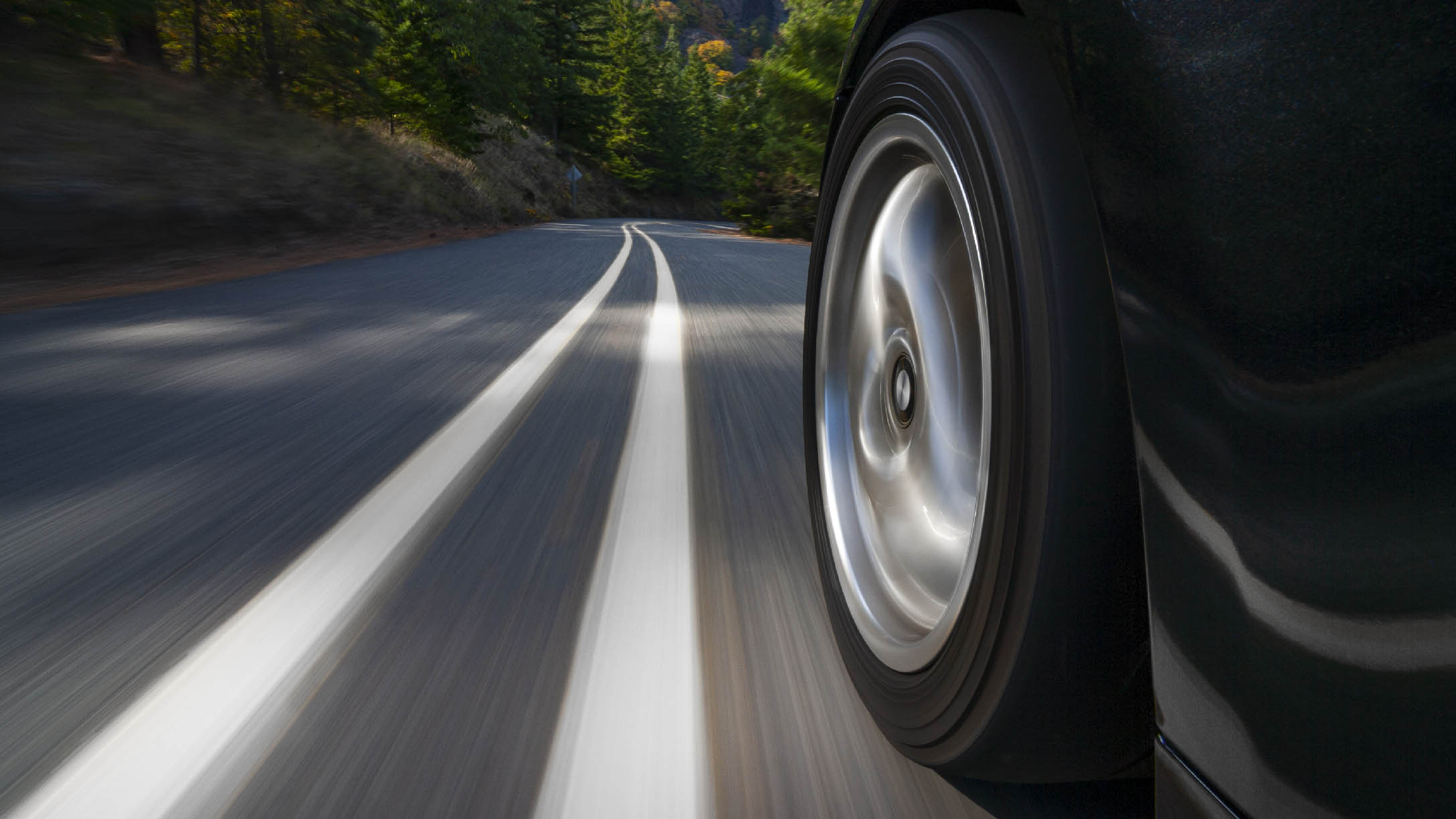 Nahaufnahme eines Autoreifens beim Fahren auf einer Straße.