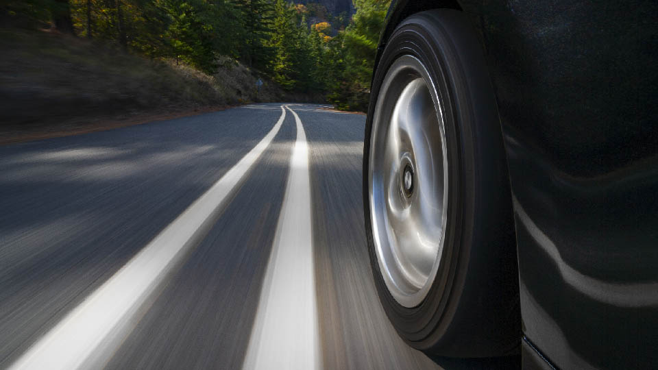 Nahaufnahme eines Autoreifens beim Fahren auf einer Straße.