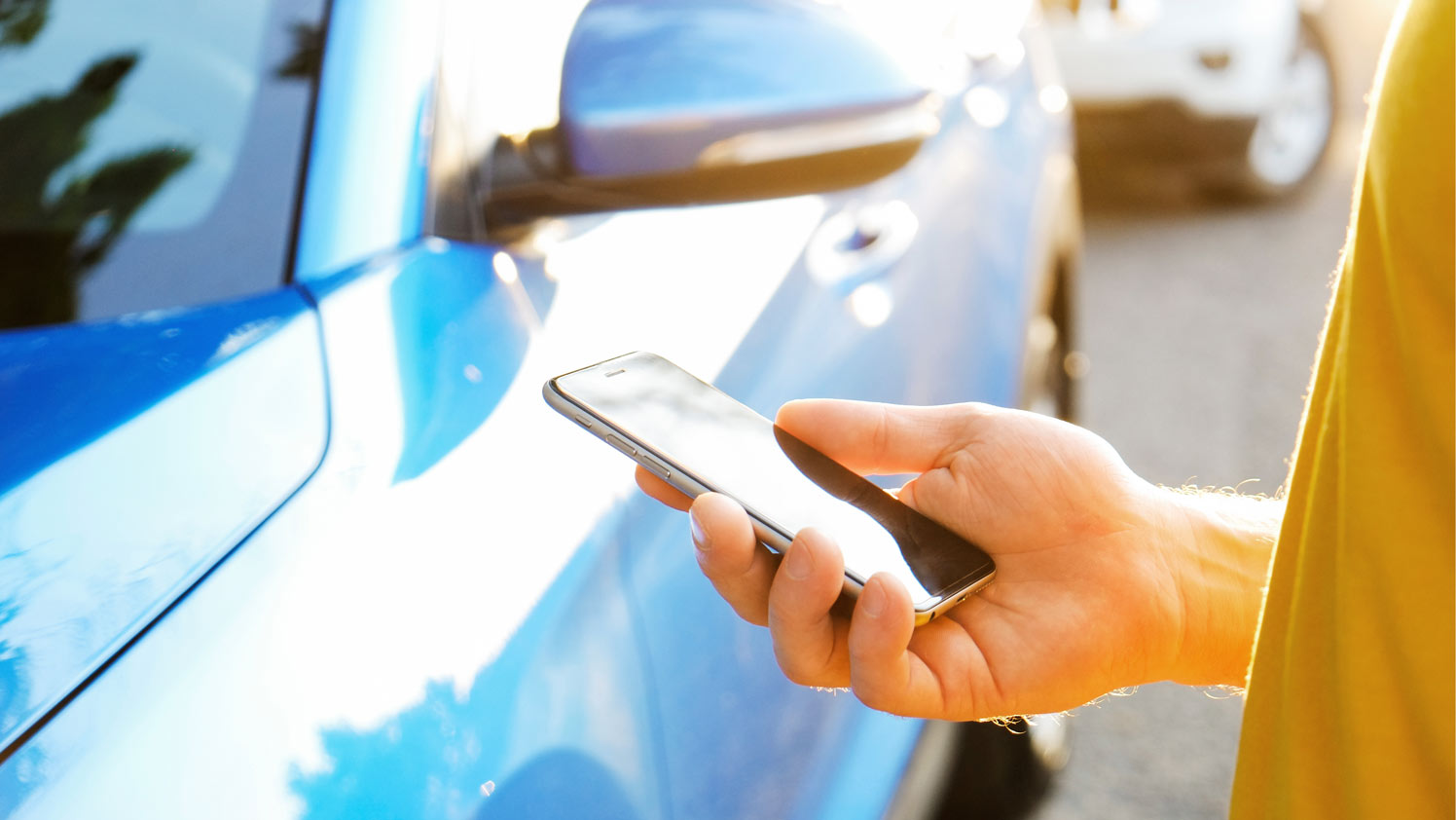 Hand beim Telefonieren neben dem Auto