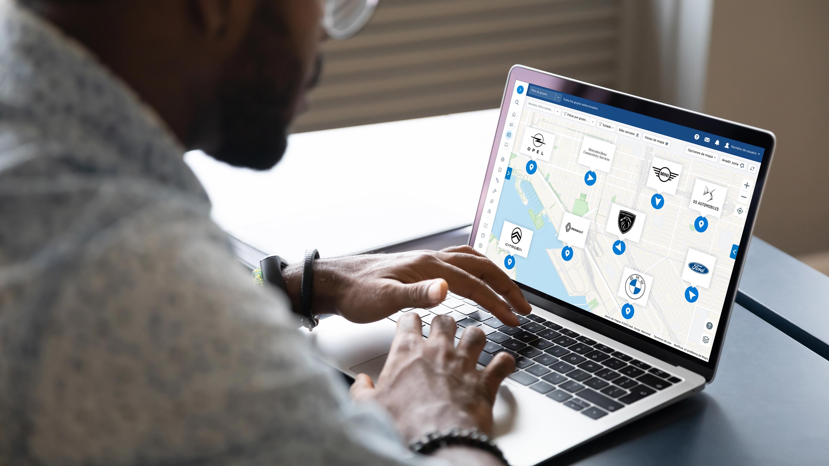 Hombre trabajando en un portátil mostrando la interfaz de usuario del mapa de mygeotab con diferentes logos de OEM