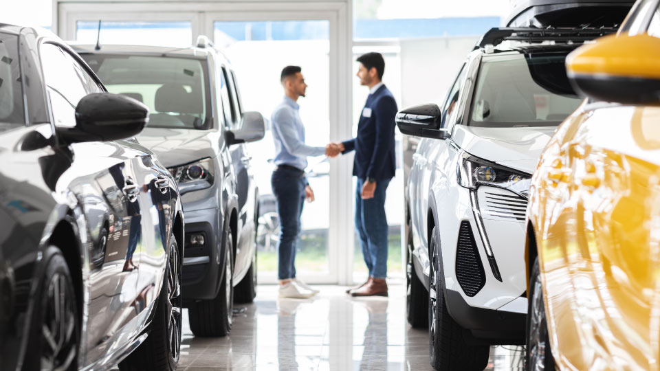 four cars lined up with two men shaking hands in the center