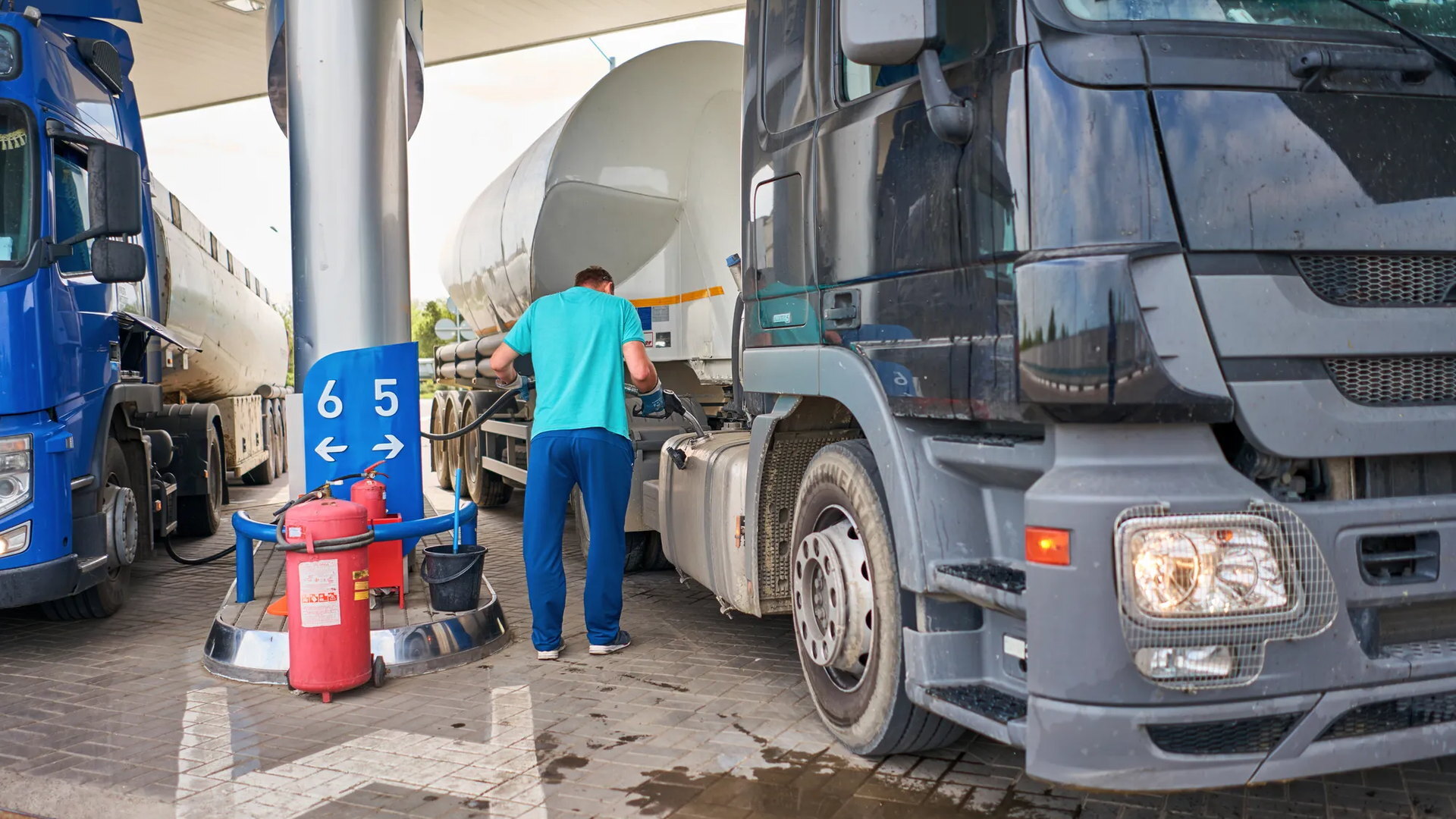 Camión cisterna repostando en una estación de servicio junto a otros vehículos de una flota de transporte.