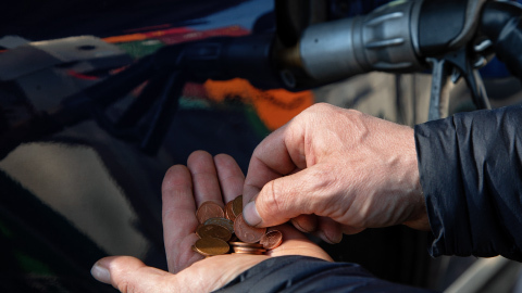 Persona con monedas ahorrando combustible