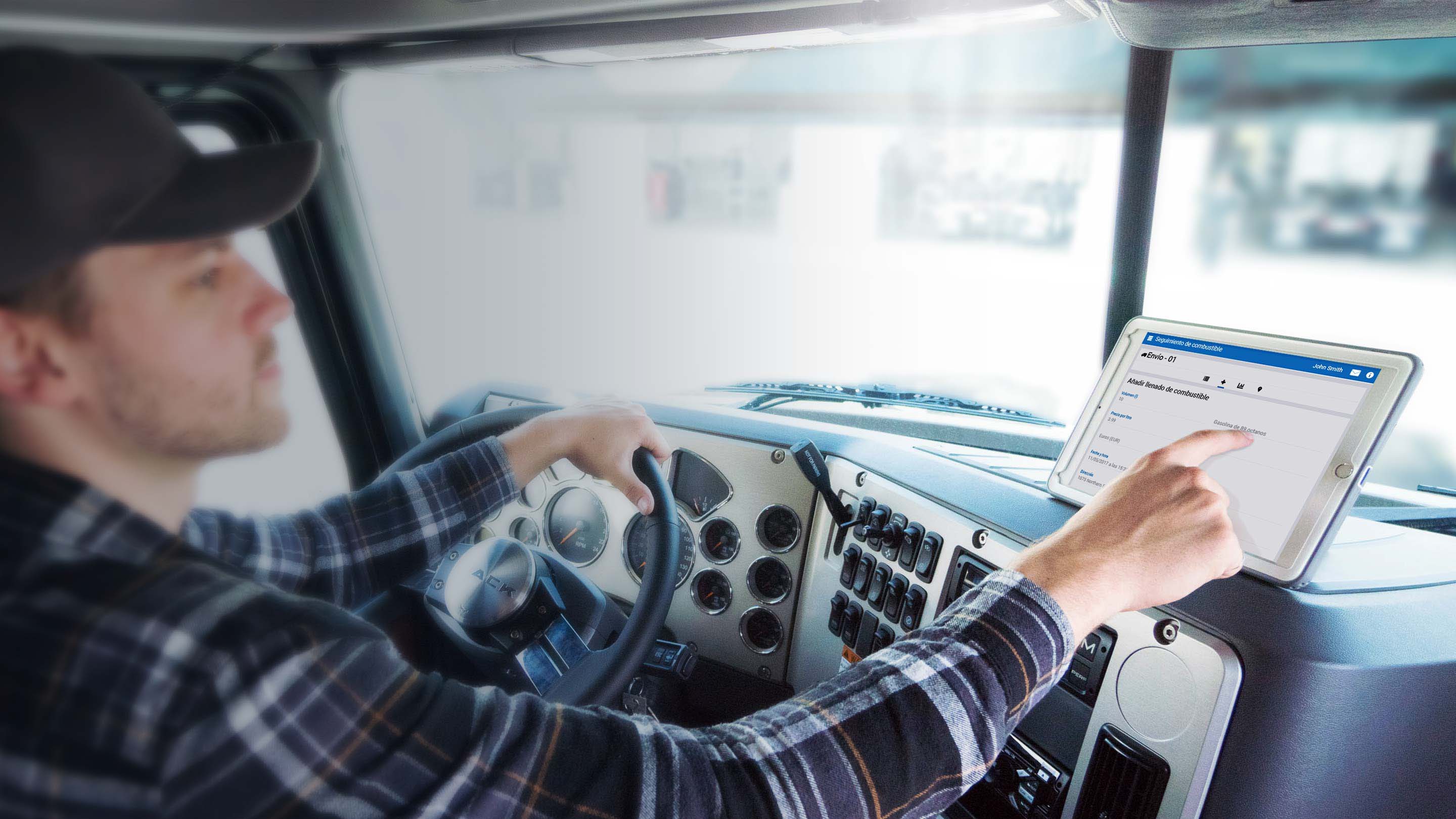 Conductor de camión en el asiento del conductor aparcado y usando una tableta con Geotab Drive en ella