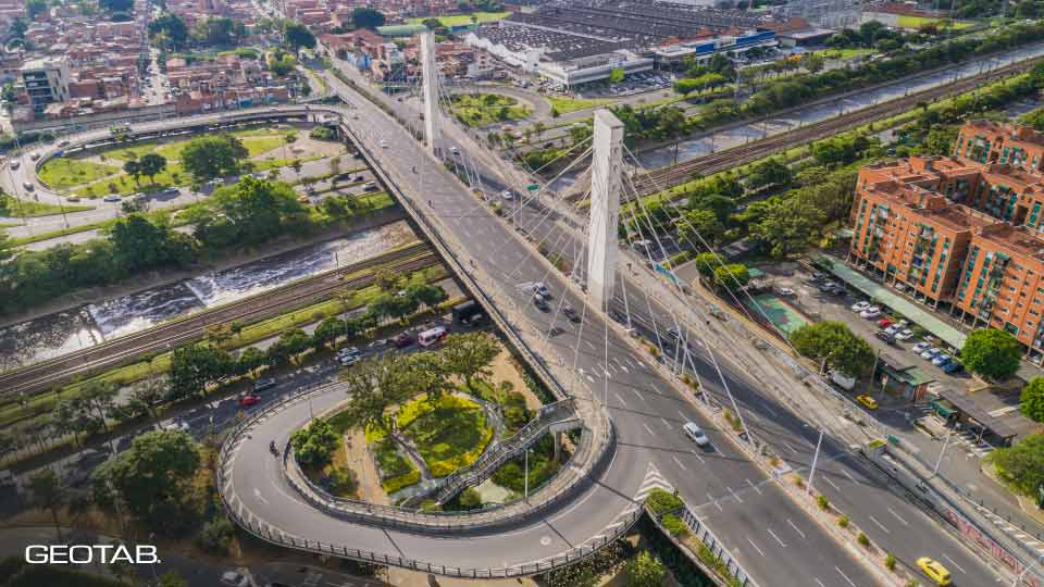 Imágen aérea de autopistas en Bogotá, de día, con vehículos circulando y áreas verdes alrededor