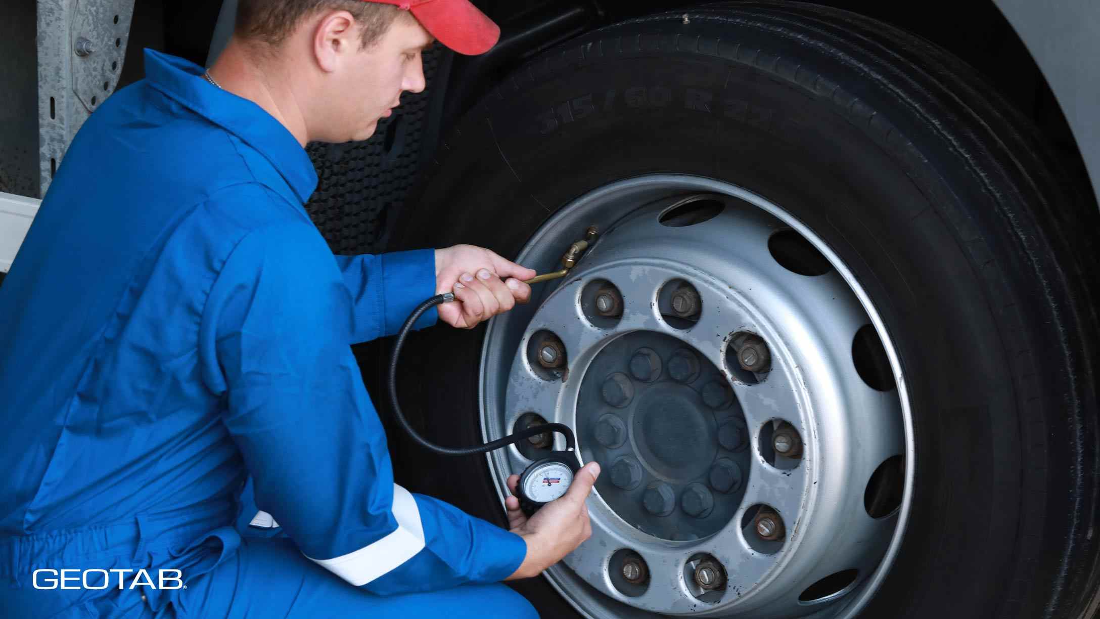 Hombre vestido de azul reparando la llanta de un vehículo pesado