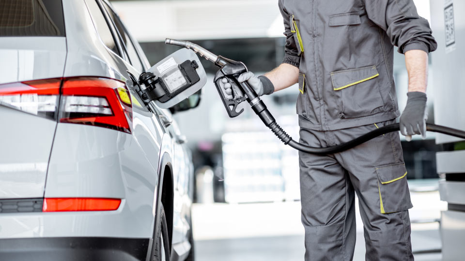 Imagen de un hombre cargando gasolina en un vehículos blanco