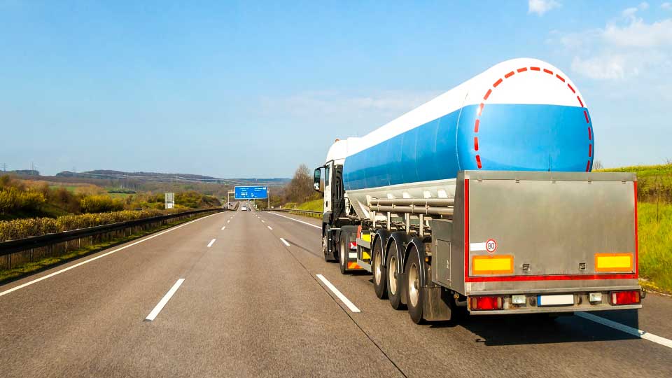 Foto de un camión pesado azul y blanco conduciendo por una carretera.