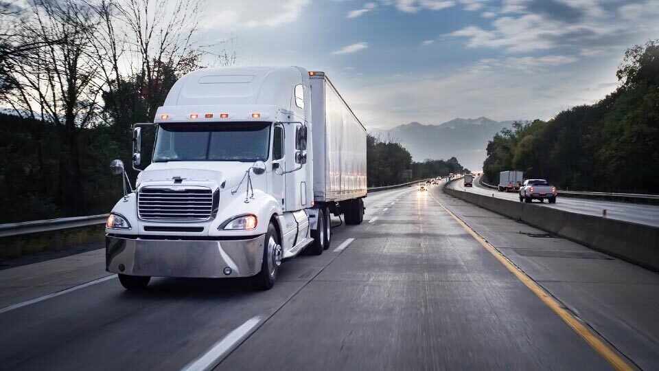 Imagen de camion blanco conducioendo en una carretera