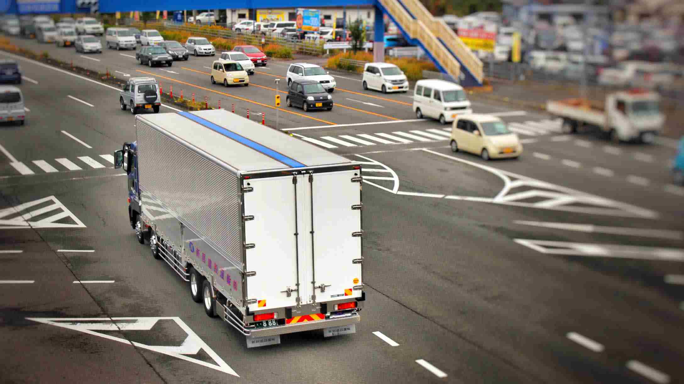 Imagen de un camión en medio de un cruce de una ciudad, con vehículos alrededor