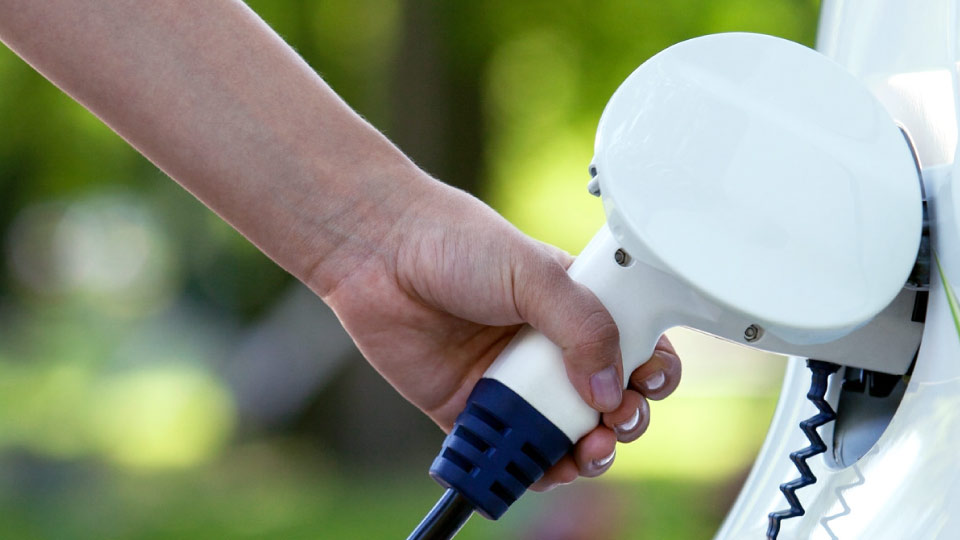 Foto de una mano cargando un vehículo eléctrico blanco