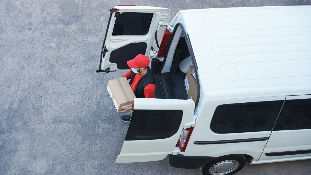 Foto de una persona tomando una caja de una camioneta blanca de última milla.