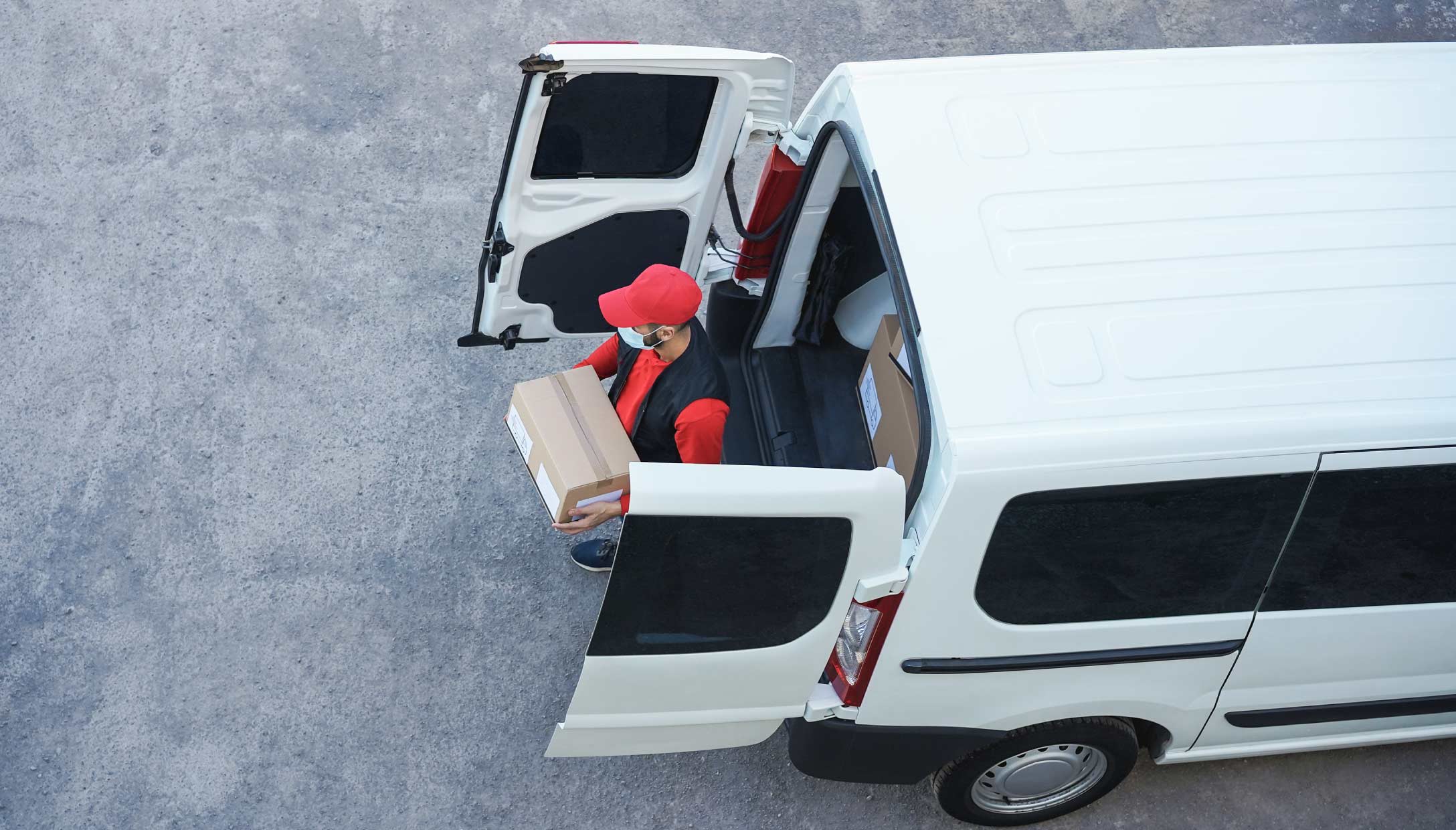 Foto de una persona tomando una caja de una camioneta blanca de última milla.