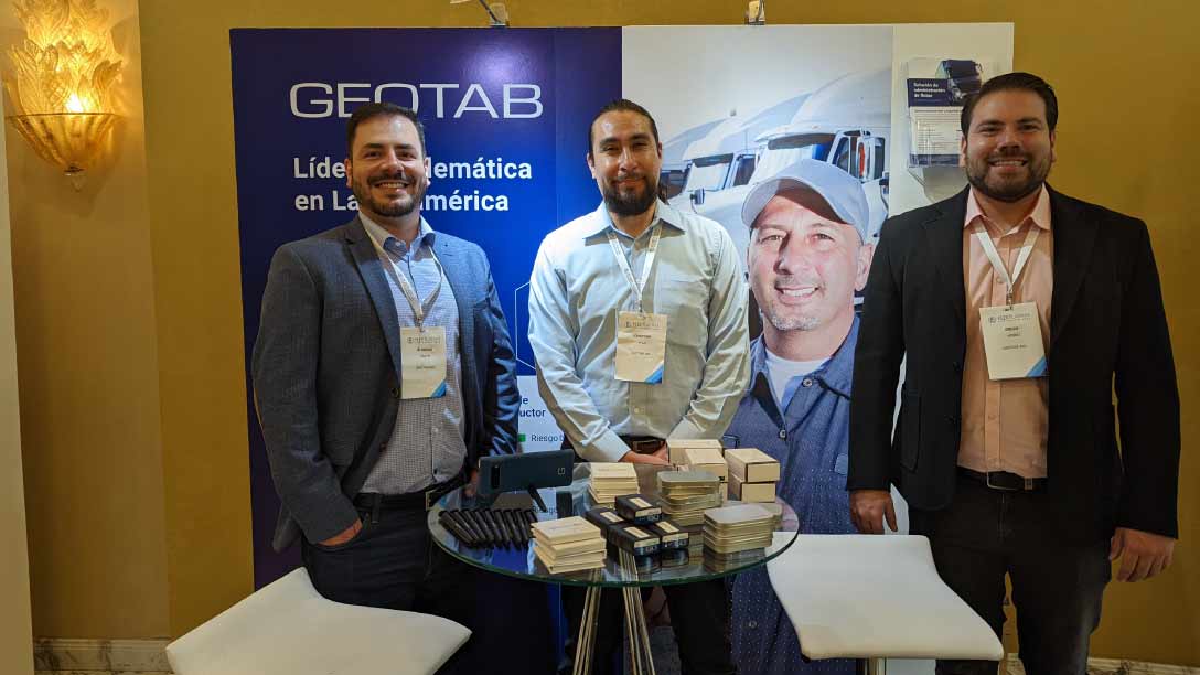 Foto de tres personas alrededor de un una mesa sonriendo.