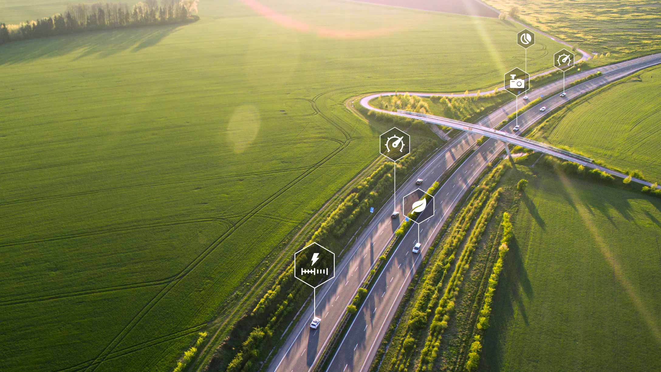 Foto de varios vehículos conduciendo por una carretera en un campo verde con símbolos de datos.