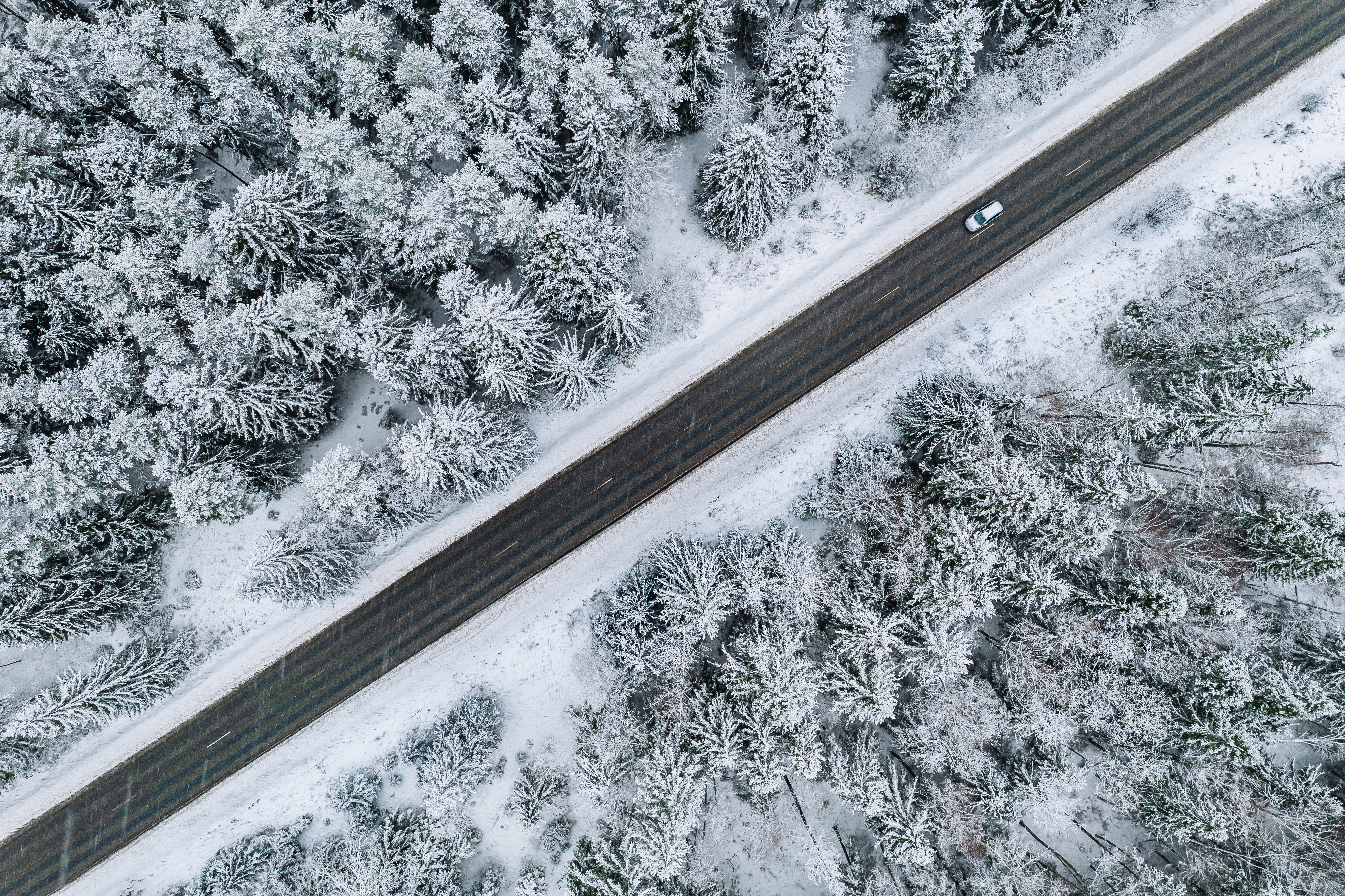 Vista aérea de un vehículo circulando por una ruta nevada, representando la operación ininterrumpida de flotas durante el invierno.