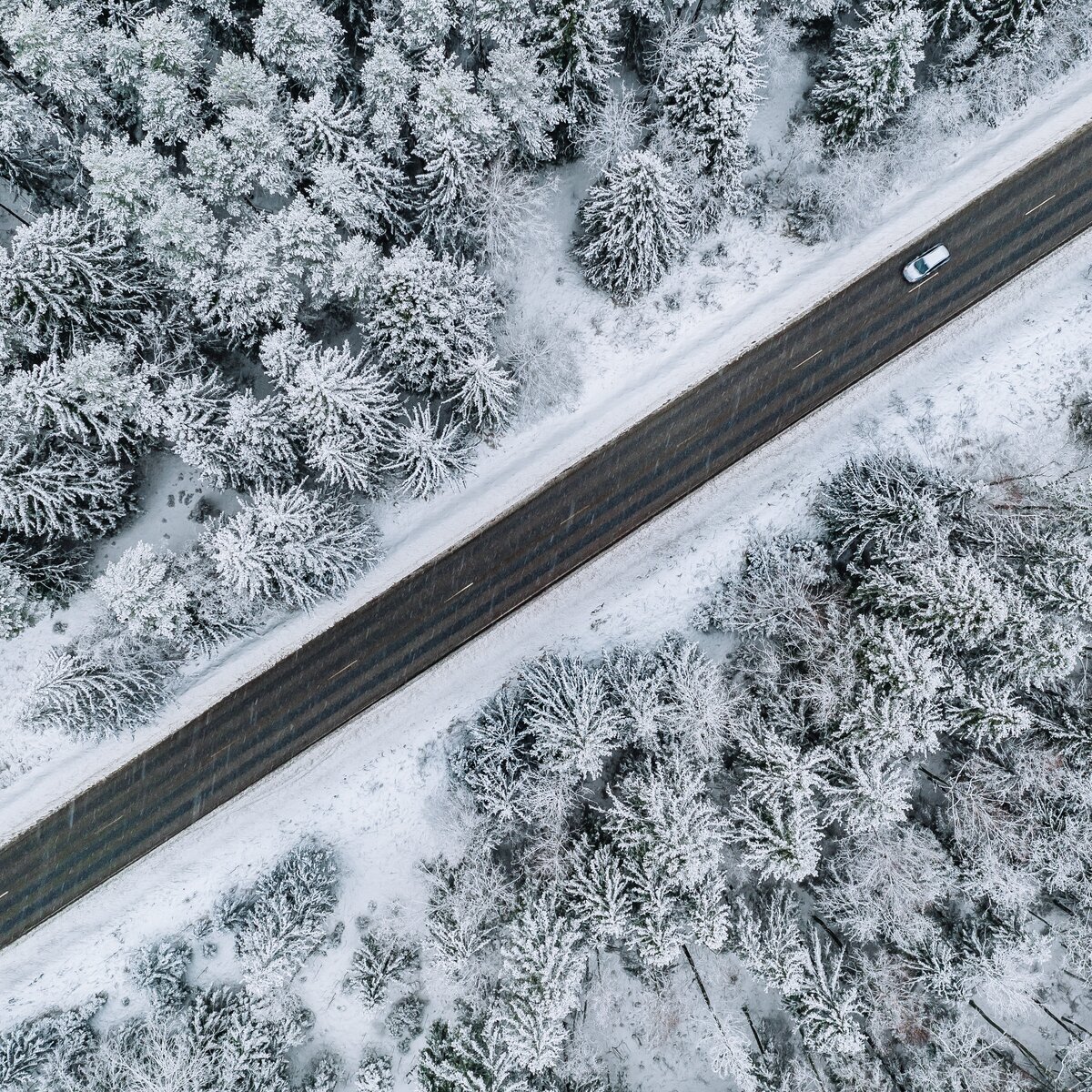 Vista aérea de un vehículo circulando por una ruta nevada, representando la operación ininterrumpida de flotas durante el invierno.