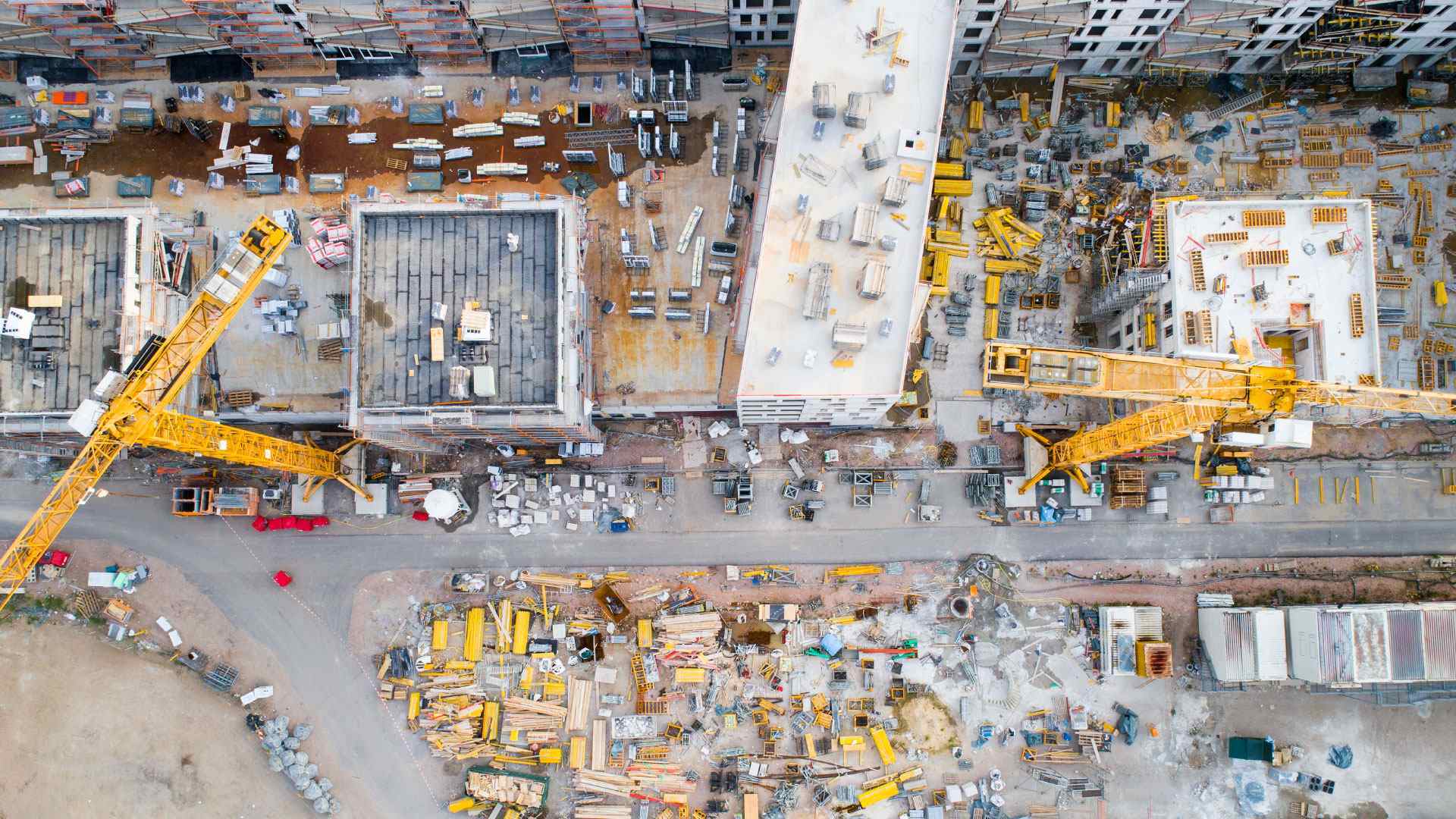 Vista aérea de un sitio de construcción con maquinaria, grúas y materiales, ilustrando los desafíos de la visibilidad y el control de activos sin rastreo.