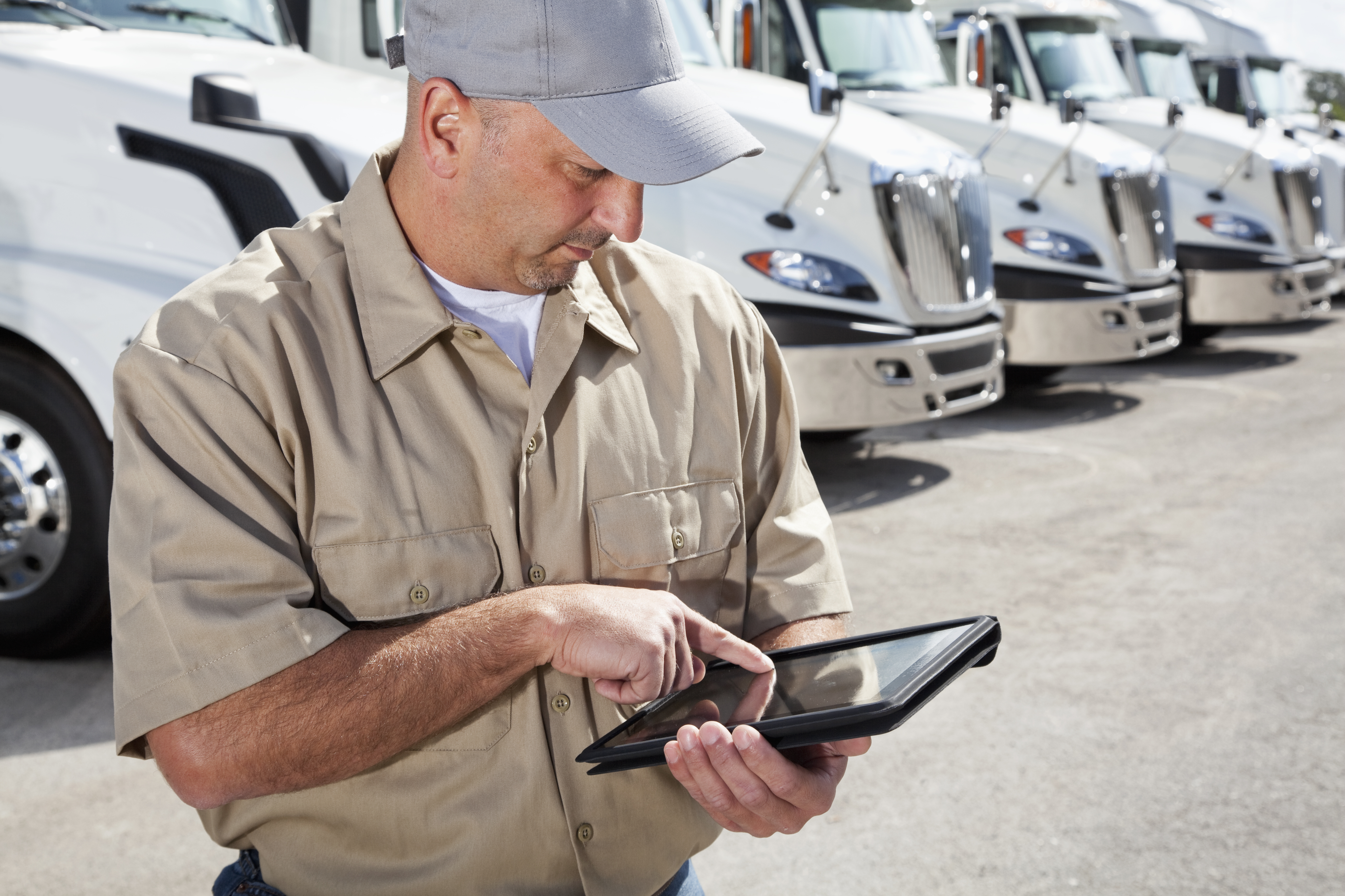Inspector de flota realizando revisiones mecánicas digitales en una tablet para automatizar el mantenimiento vehicular.
