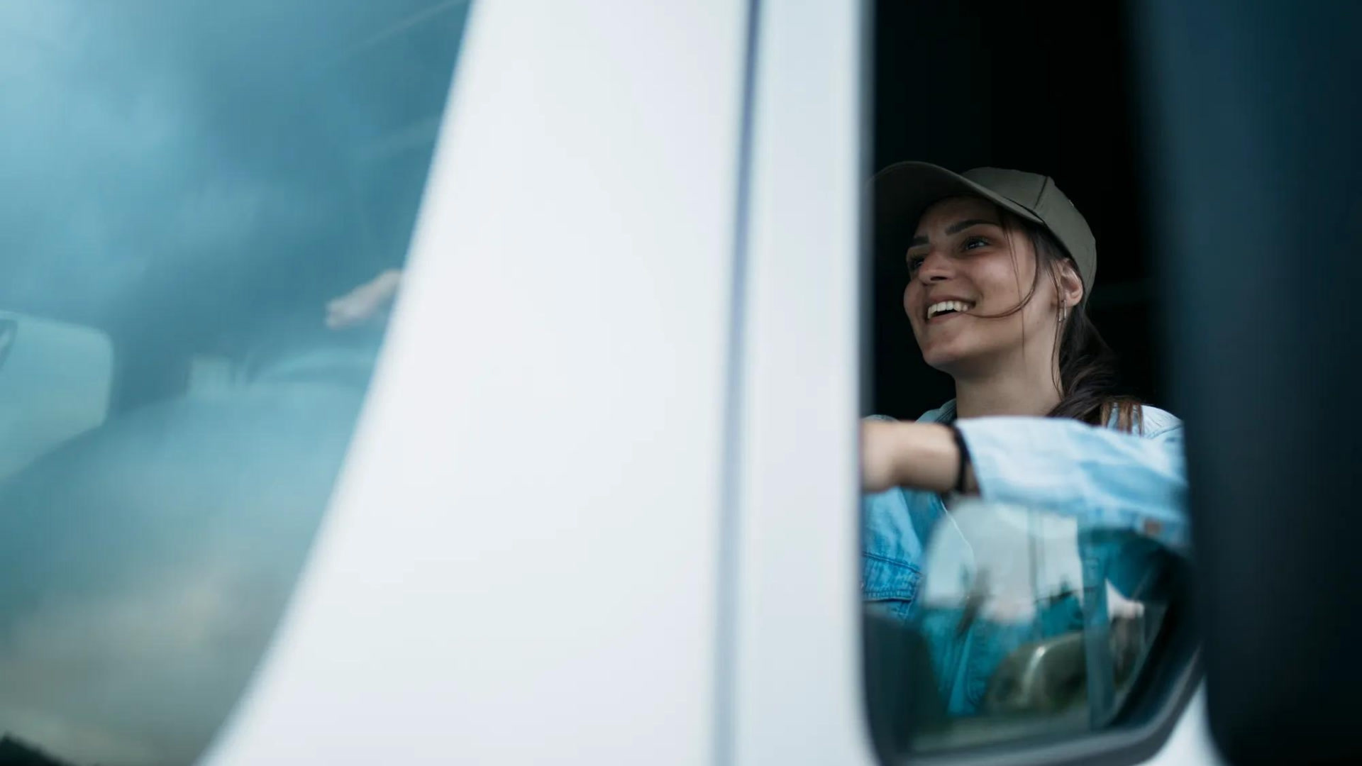 Motorista de caminhão sorrindo enquanto dirige, refletindo confiança e segurança graças à cultura de coaching na frota.