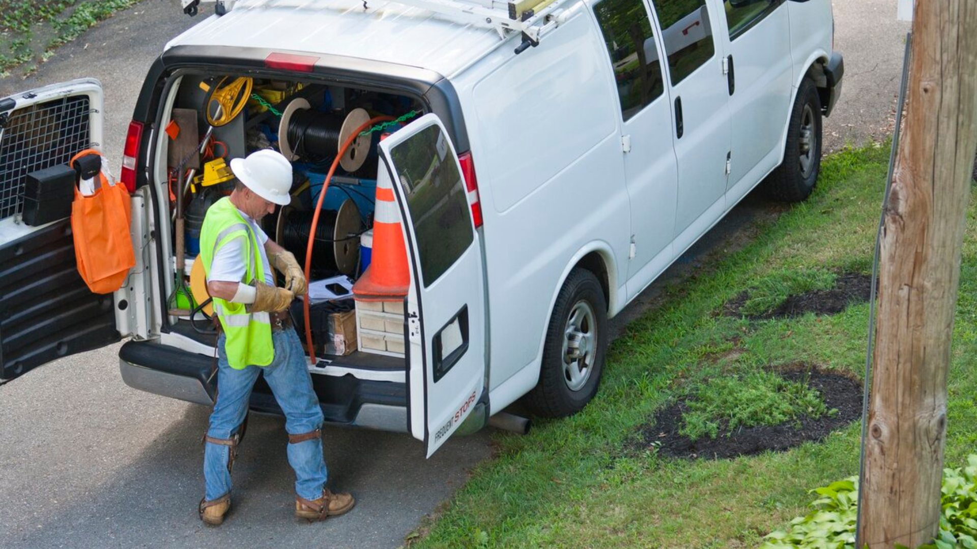 Ein Versorgungsarbeiter wartet Geräte im offenen hinteren Teil eines weißen Lieferwagens.