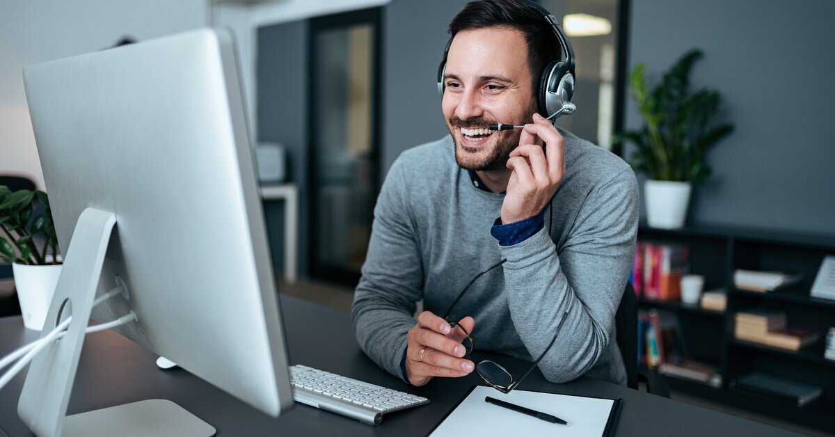 Homme souriant avec casque dans un bureau.