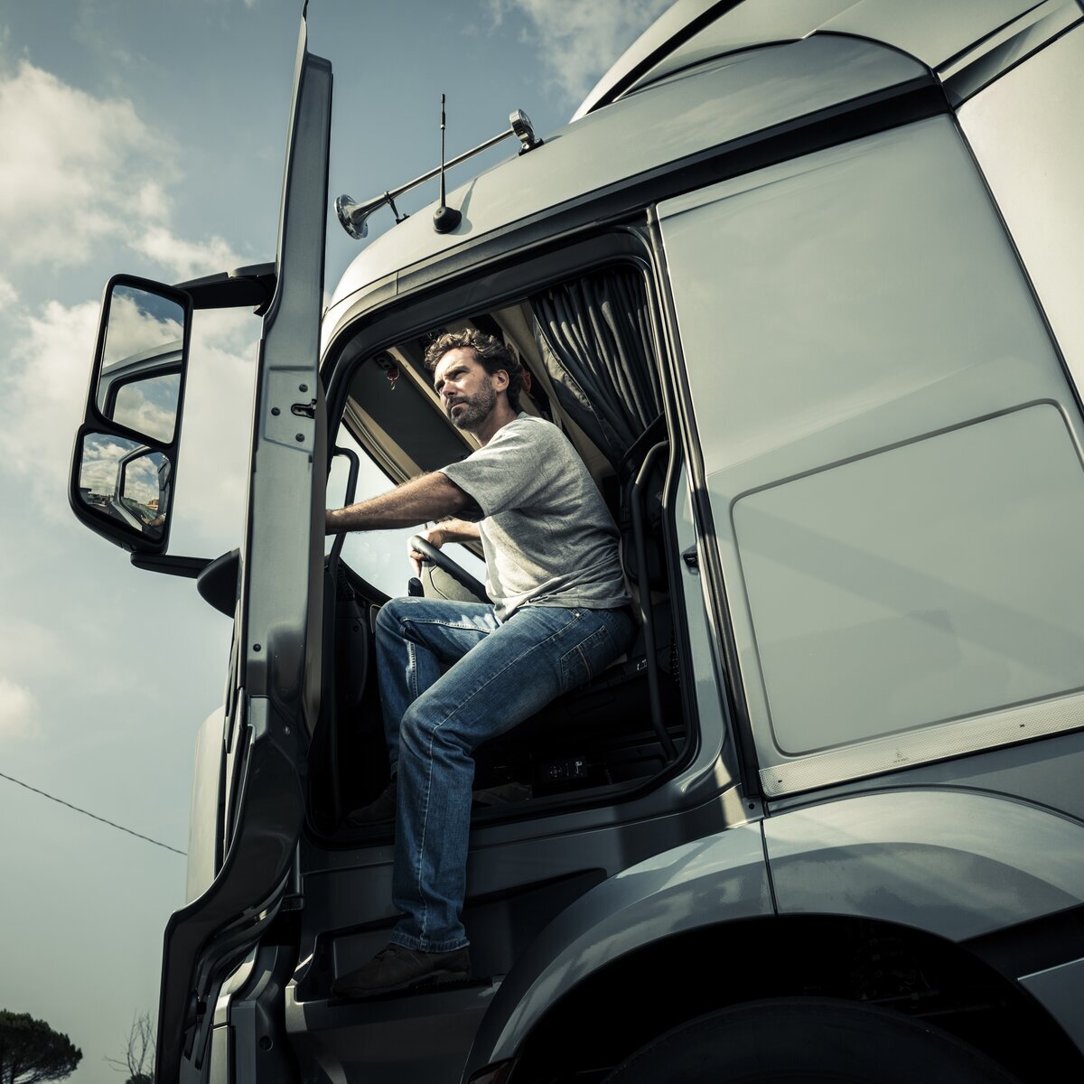 Un chauffeur de camion ouvrant la portière d'un camion blanc.