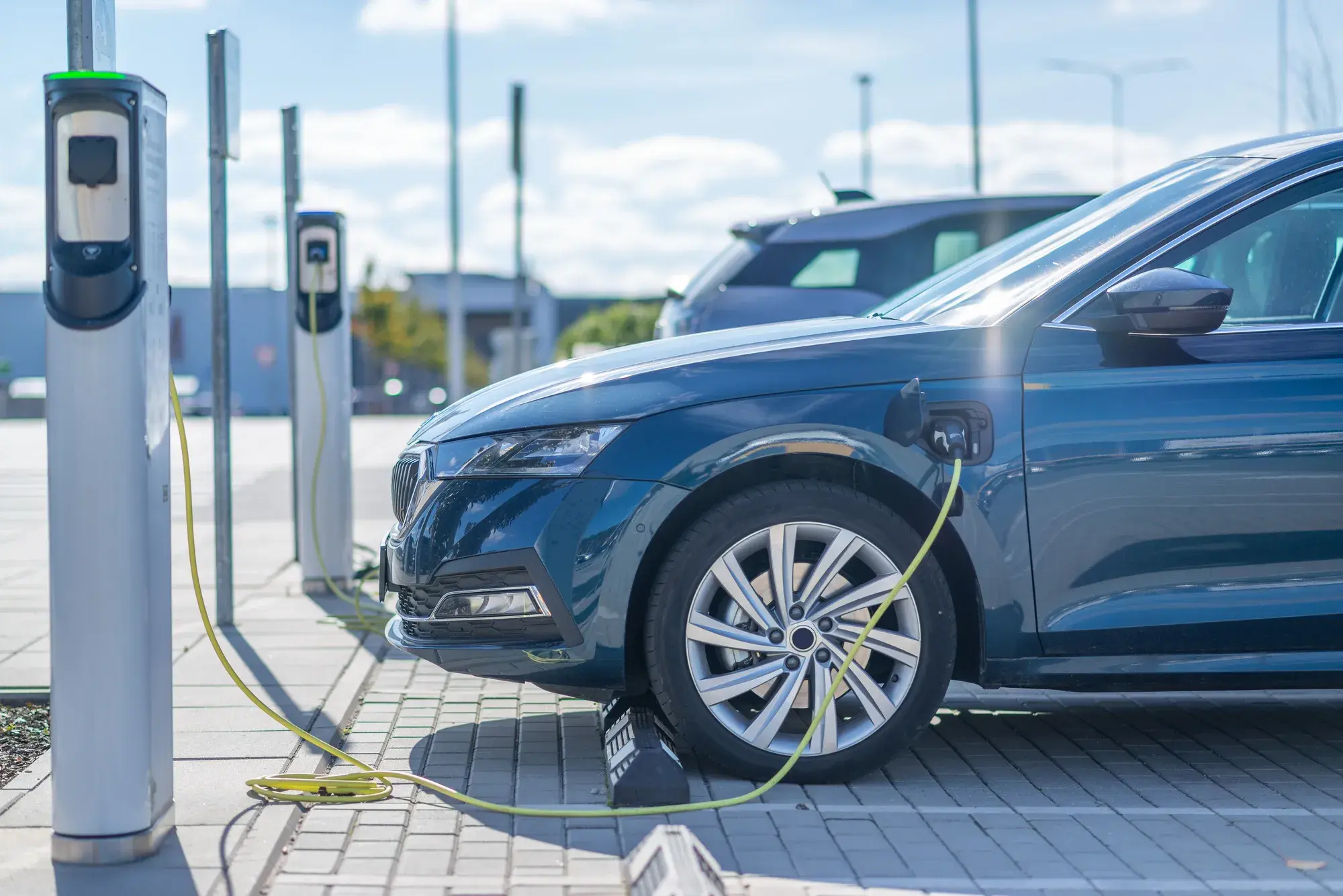 Une voiture électrique bleue branchée à une borne de recharge extérieure.