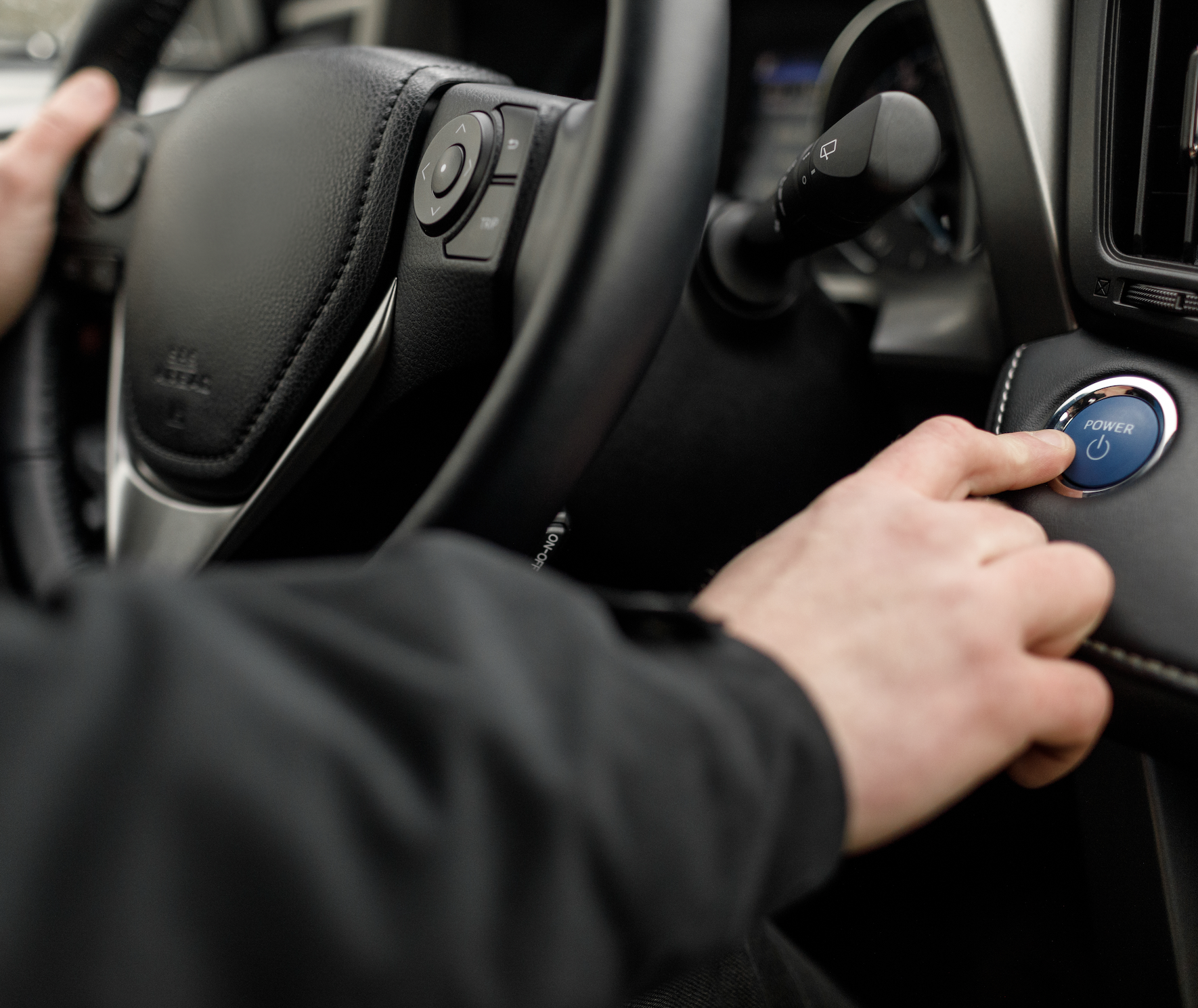 Un homme appuyant sur le bouton de démarrage dans son véhicule électrique.