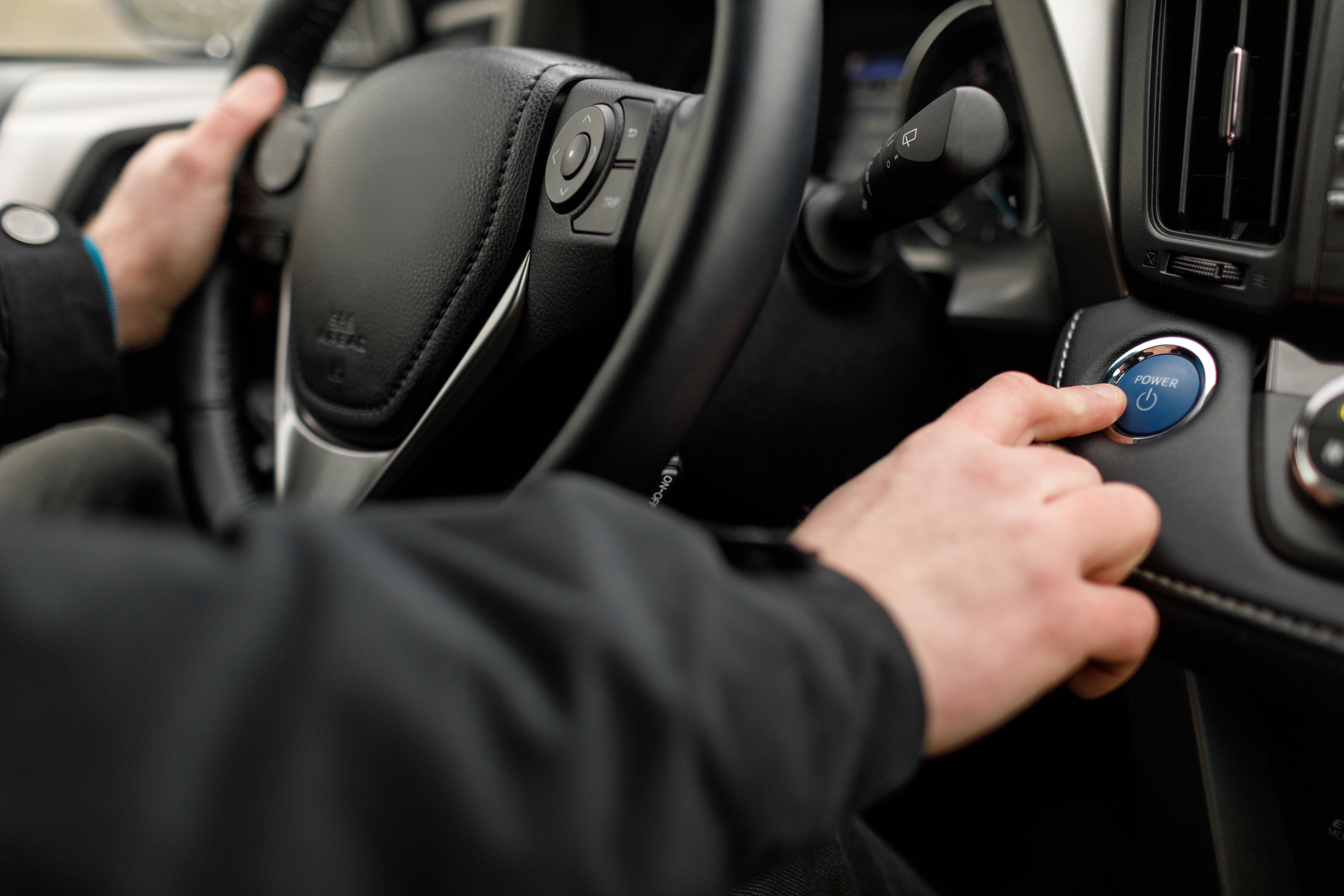 Un homme appuyant sur le bouton de démarrage dans son véhicule électrique.