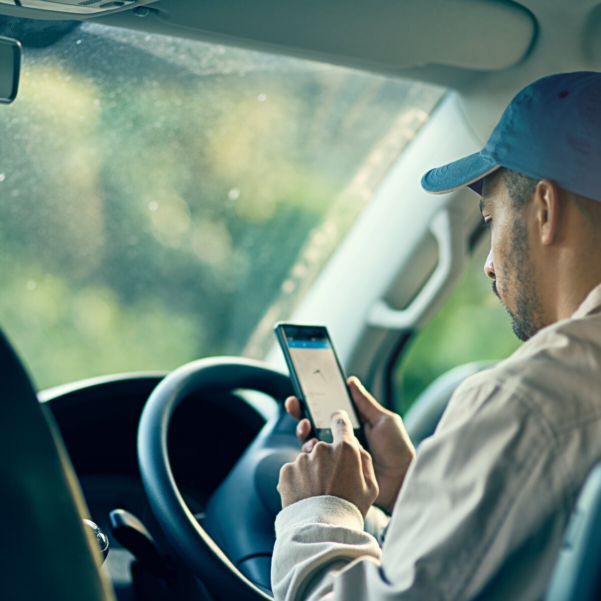 Conducteur qui utilise un téléphone portable dans l'habitacle d'une voiture.