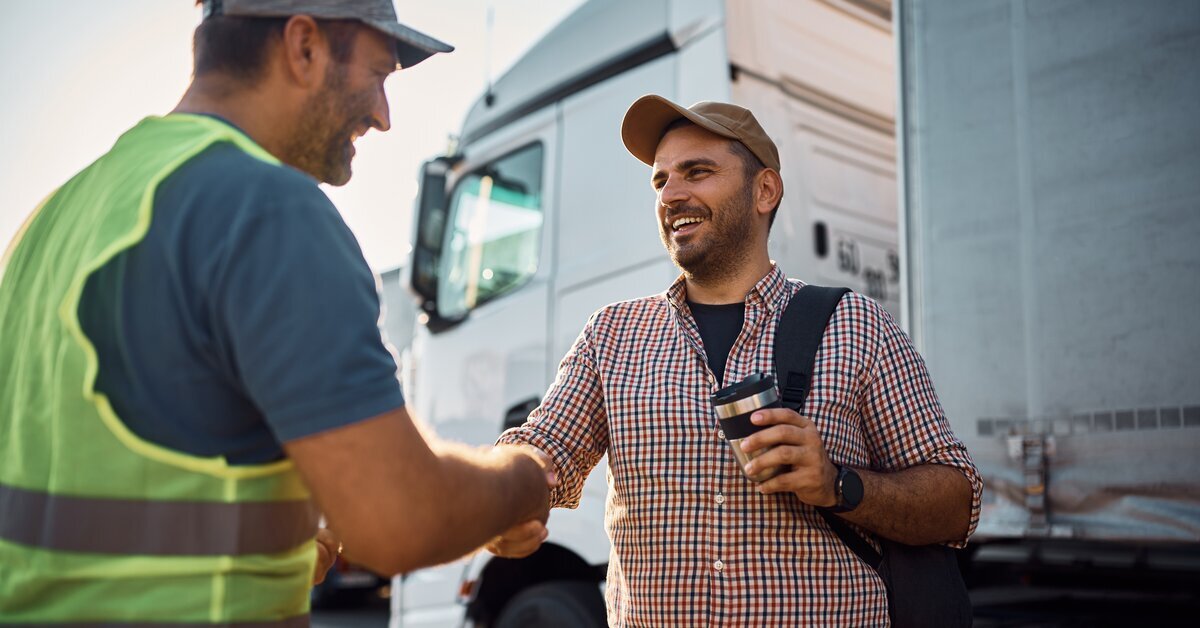 Deux hommes souriants qui se serrent la main devant un camion.