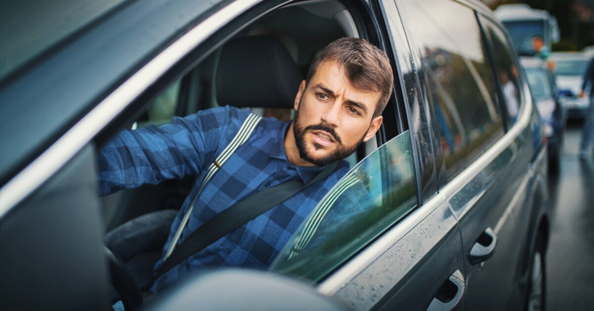 Homme dans une voiture qui regarde l'extérieur par la fenêtre.