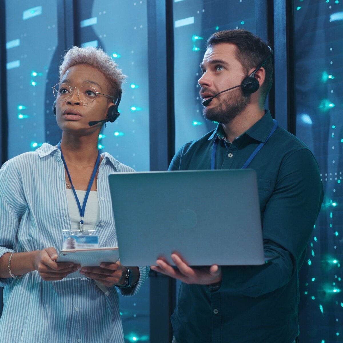 Deux professionnels de l'informatique travaillent avec un ordinateur portable et une tablette dans un centre de données.