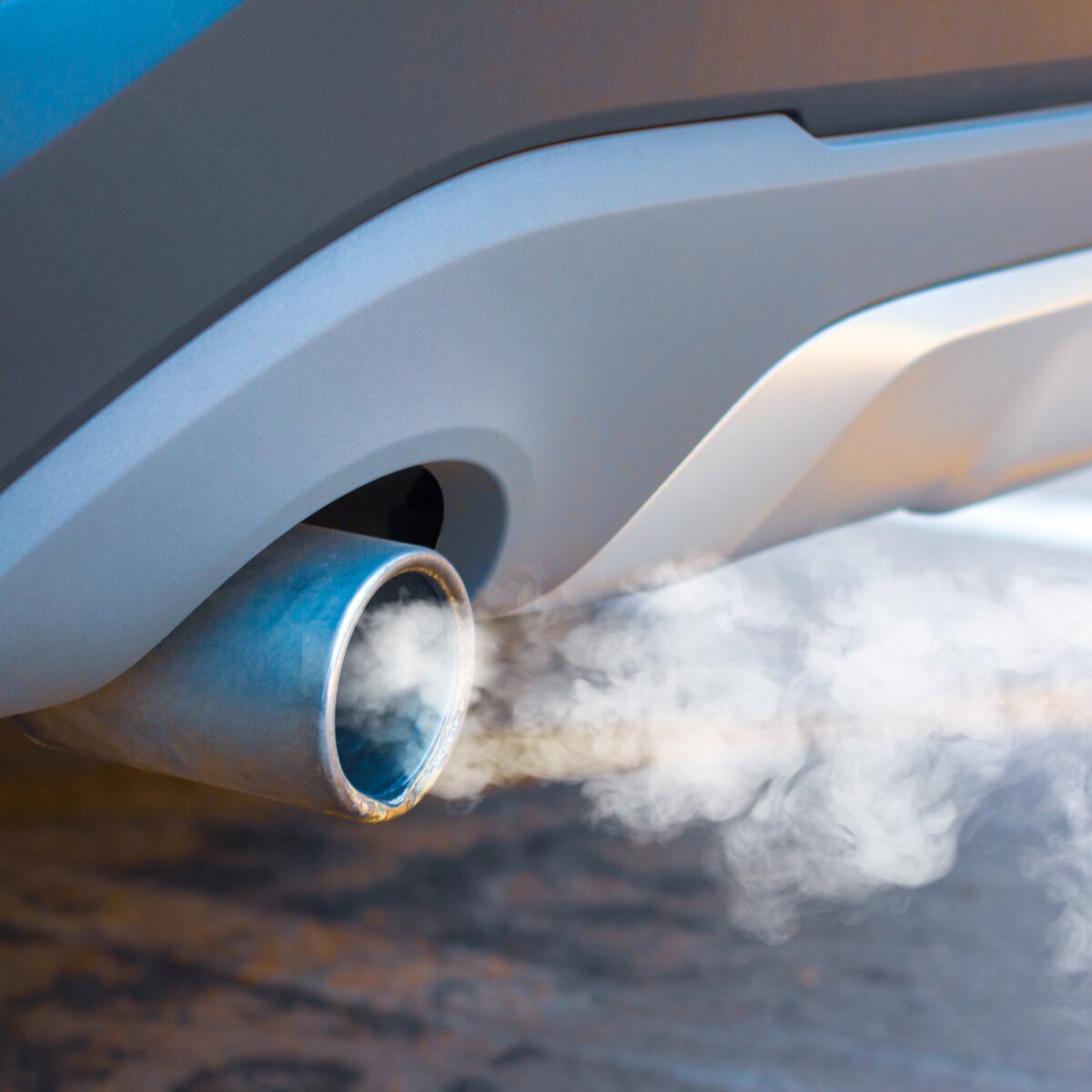 Tuyau d'échappement d'une voiture d'où s'échappe de la fumée blanche, illustrant les émissions.