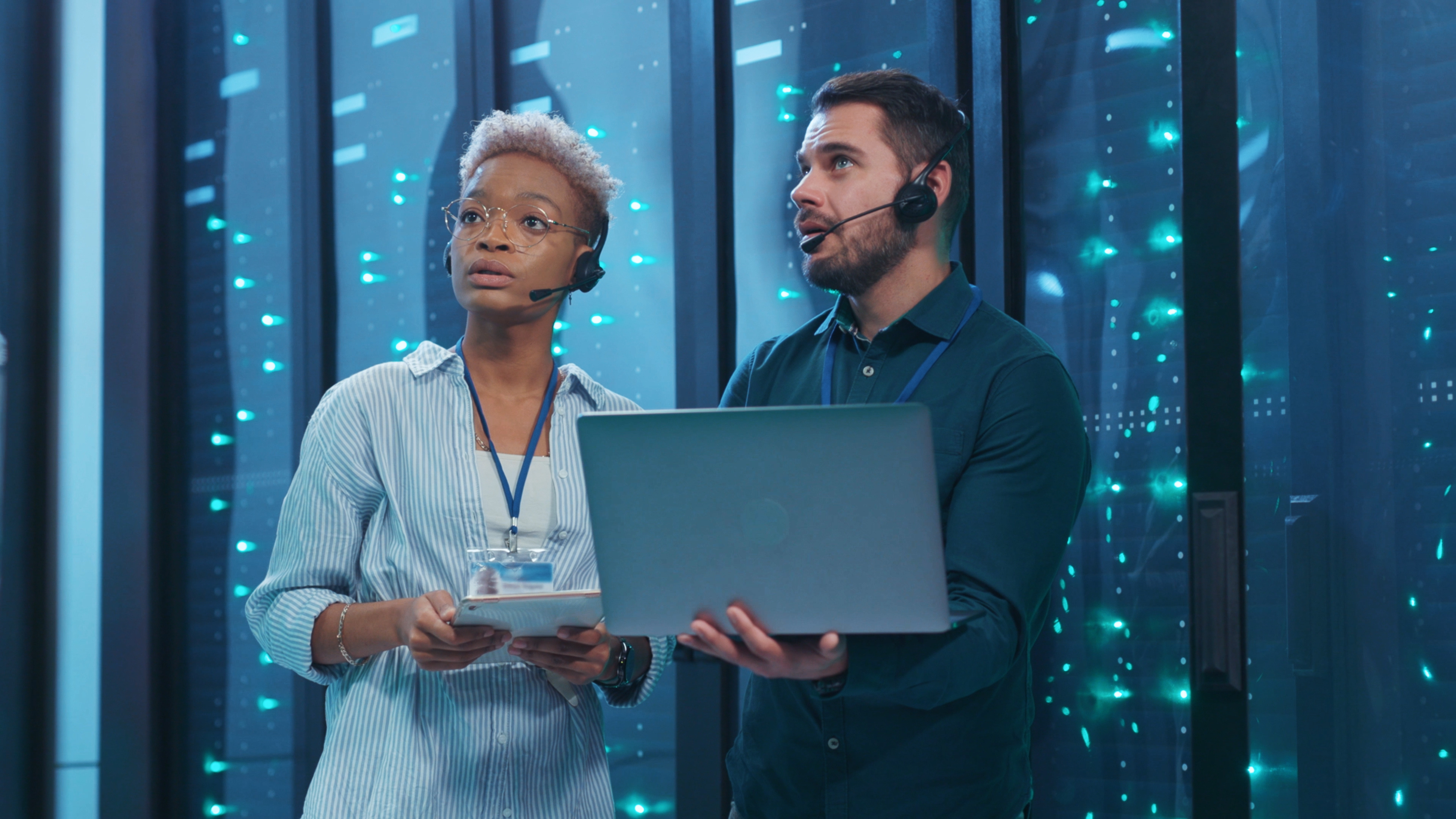 Deux professionnels de l'informatique travaillent avec un ordinateur portable et une tablette dans un centre de données.