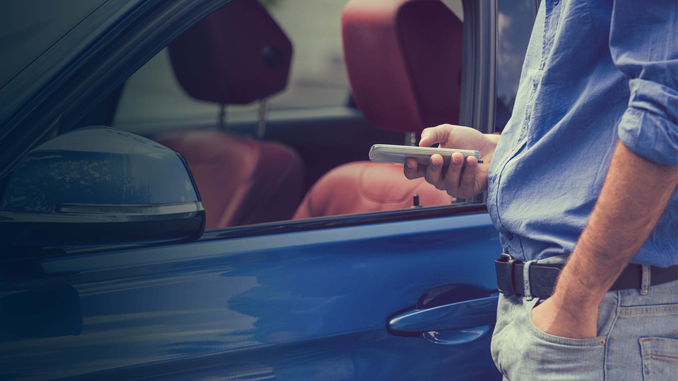 Persona de pie fuera de un coche sosteniendo un smartphone