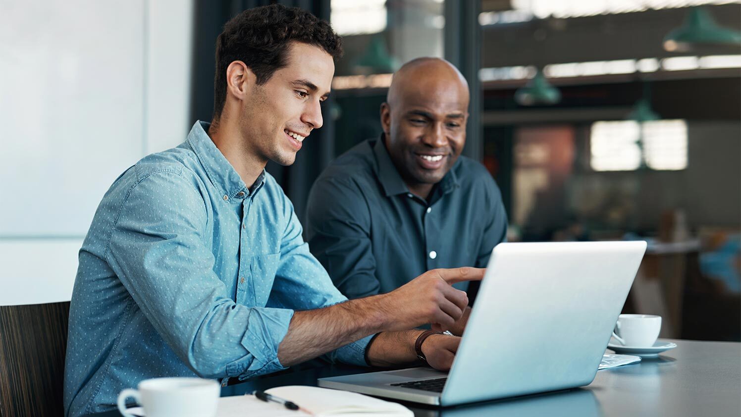 two people working at a laptop smiling