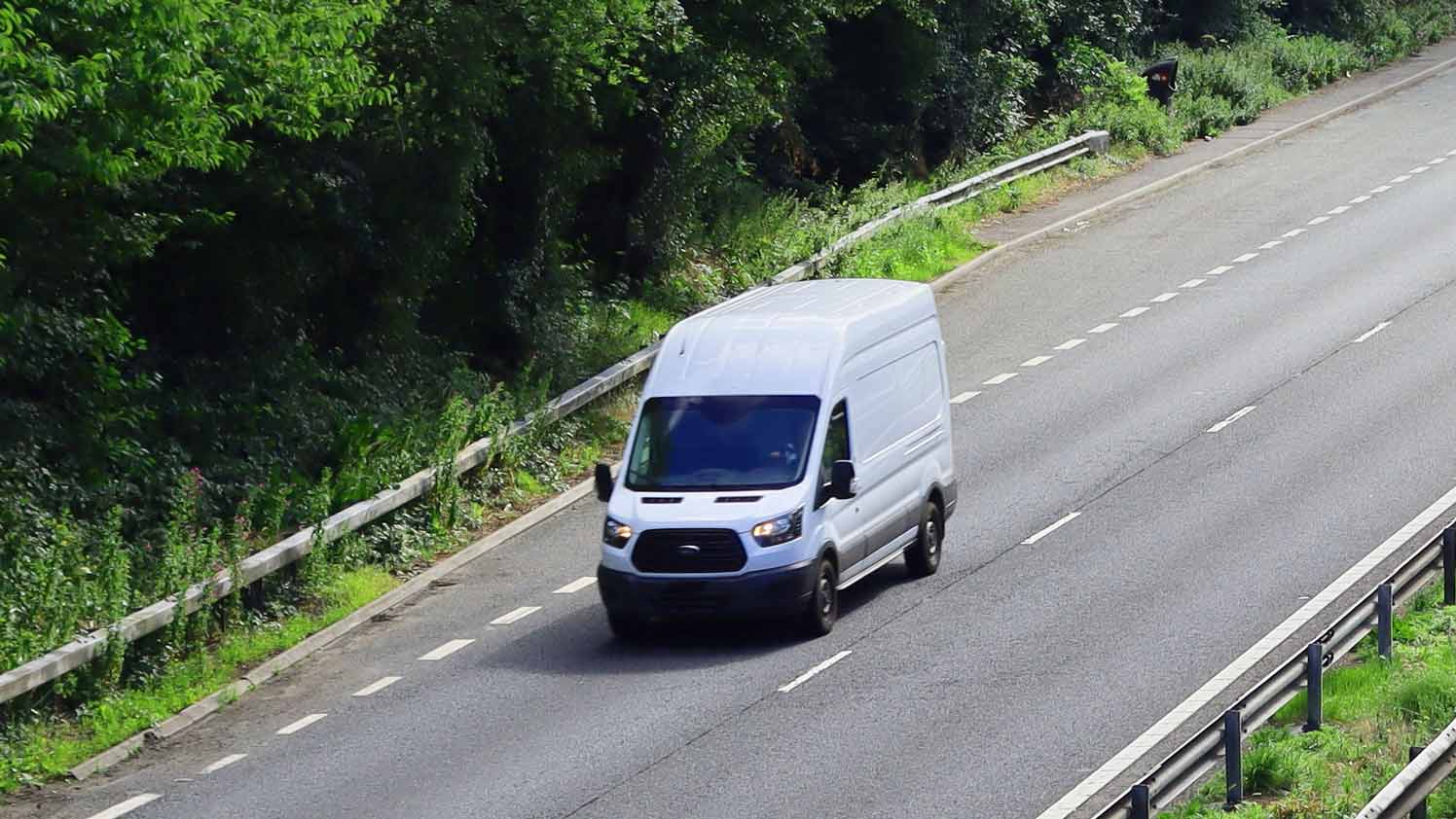 Furgoneta blanca circulando por una carretera de dos carriles