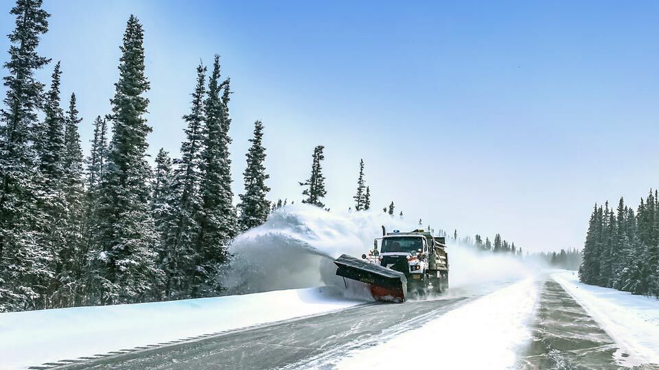 Snow plow removing snow from side of road